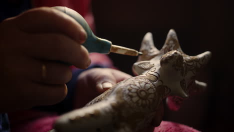 Closeup-woman-hands-decorating-product-in-pottery.-Ceramist-painting-toy-deer