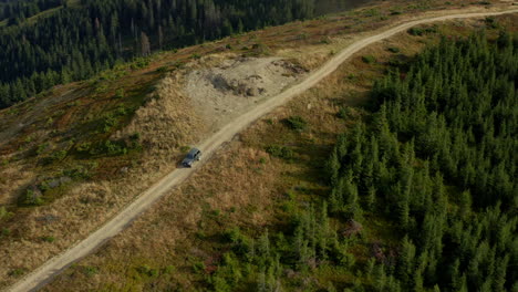 Drone-mountain-roadtrip-car-going-to-rocky-peak-green-trees-growing-scene