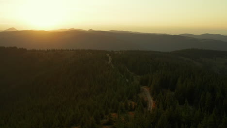 Drone-sunset-in-mountain-forest-view-against-bright-orange-sun-at-golden-sky