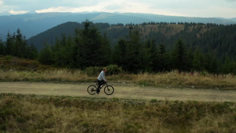 Mountain-cycling-drone-view-against-stunning-spruce-forest-hills-enjoying-time
