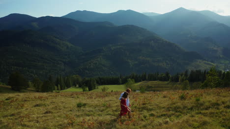 Lovers-in-mountains-walking-grass-enjoying-amazing-landscape-blue-sky-background