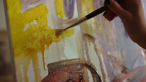 Creative-painter-holding-paintbrush-on-canvas.-Woman-hand-making-brush-stroke.