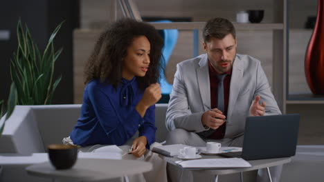 Mixed-race-business-couple-working-laptop-computer-at-remote-workplace-office.