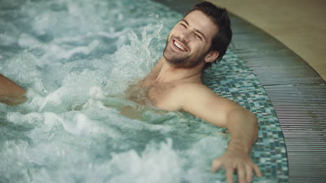 Smiling-man-relaxing-in-jacuzzi-spa-indoor.-Sexy-guy-resting-in-whirlpool-bath