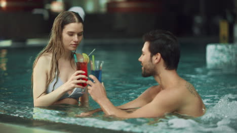 Young-couple-relaxing-at-whirlpool-indoor.-Attractive-couple-drinking-cocktails