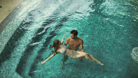Top-view-of-joyful-couple-bathing-at-spa-resort.-Cheerful-couple-enjoying-pool
