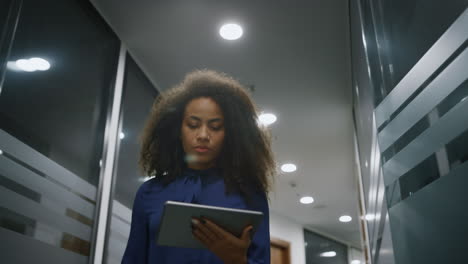 Afroamerikanische-Geschäftsfrau,-Die-Im-Büro-Geht-Und-In-Der-Firma-Nach-Einem-Digitalen-Tablet-Sucht.
