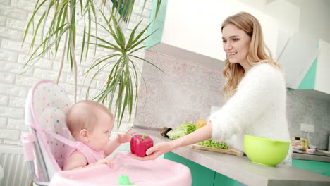 Mother-with-baby-on-kitchen.-Healthy-baby-food.-Woman-cooking-vegetables