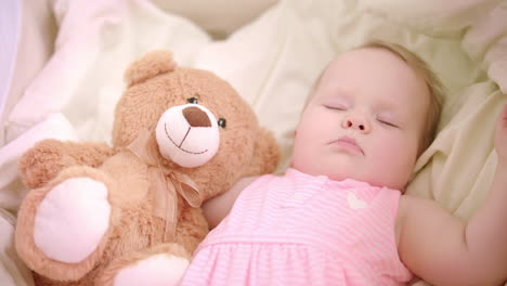 Baby-girl-sleeping-with-toy-in-crib.-Sweet-bedtime.-Little-girl-dream-in-bed
