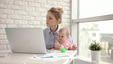 Working-mother-with-baby-at-table.-Working-mom-with-beautiful-infant-on-hands