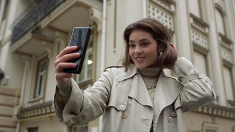 Cheerful-woman-speaking-during-video-call.-Girl-waving-hand-on-phone-camera.