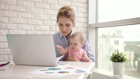 Woman-with-baby-not-concentrated-at-work.-Business-mother-looking-documents