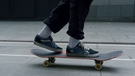 Unrecognizable-man-feet-balancing-on-skateboarding-on-city-street-closeup.