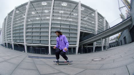 Patinador-Enfocado-Cabalgando-Sobre-Fondo-Urbano.-Chico-Deportivo-Saltando-Sobre-Skate-Al-Aire-Libre.