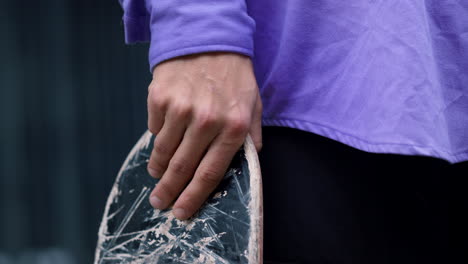 Closeup-man-hand-holding-longboard-outside.-Sporty-guy-preparing-skate-outdoor.