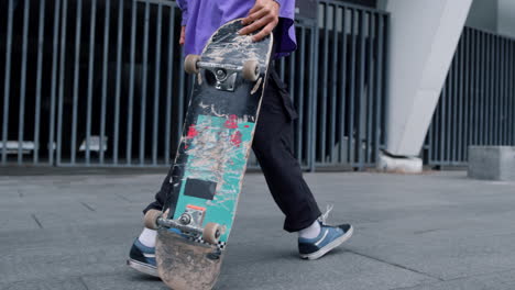 Unknown-man-carrying-skateboard-outdoor.-Skater-walking-with-longboard-in-hand