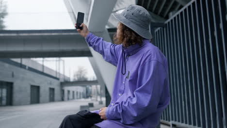 Stylish-hipster-taking-selfie-on-smartphone.-Focused-man-posing-on-phone-camera.