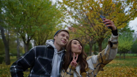 Funny-young-couple-in-love-taking-selfie-on-their-mobile-phone-in-autumn-park.
