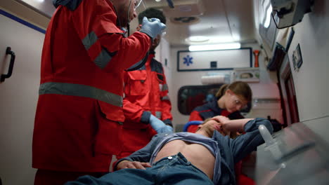 Mixed-race-medical-team-examining-man-abdomen-in-emergency-car