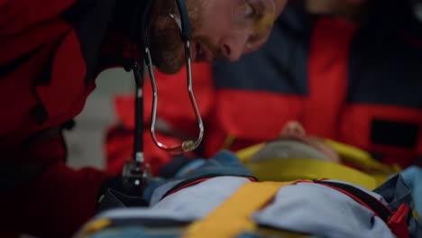 Paramedic-listening-to-patient-heartbeat.-Victim-lying-on-stretchers