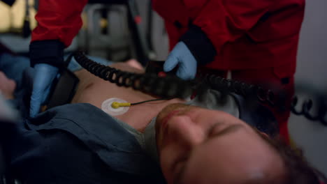 Doctor-rescuing-patient-with-external-defibrillator.-Paramedic-reanimating-man