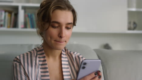 Serious-freelancer-typing-messages-in-pajamas-closeup.-Focused-girl-hold-phone