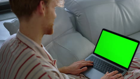 Guy-using-green-laptop-computer-closeup.-Online-teacher-talking-video-conference