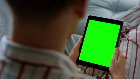 Man-holding-tablet-videocalling-in-pajamas-closeup.-Chroma-key-screen-device
