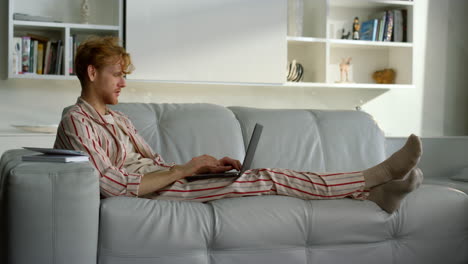 Freelancer-talking-home-online-resting-in-pajamas.-Ginger-man-working-remotely