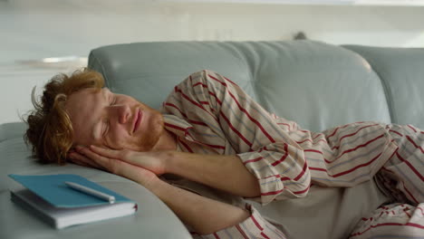 Relaxed-guy-sleeping-sofa-in-pajamas-closeup.-Smiling-freelancer-enjoy-daydream