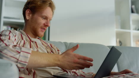 Millennial-guy-talking-online-at-home-closeup.-Relaxed-businessman-using-laptop