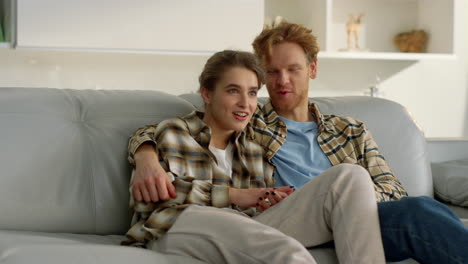 Happy-girlfriend-watching-tv-with-ginger-man-on-weekend.-Married-couple-resting