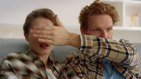 Married-people-watching-tv-program-at-home-closeup.-Ginger-man-close-woman-eyes.