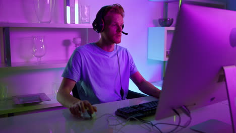 Man-having-live-stream-in-neon-room.-Joyful-gamer-commenting-actions-in-headset