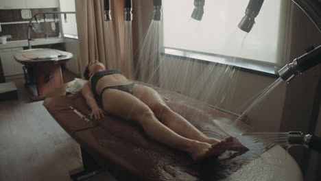 Pretty-woman-having-vichy-shower-in-spa.-Bikini-girl-lying-on-massage-table.