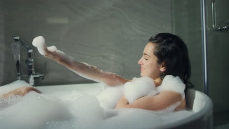 Happy-girl-having-fun-in-bathtub-indoors.-Gorgeous-woman-enjoying-bath-in-hotel