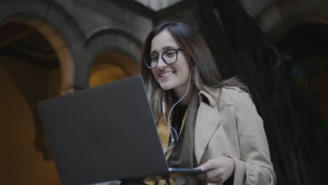 Student-using-laptop-for-video-call-at-university.-Girl-waving-to-friend-online
