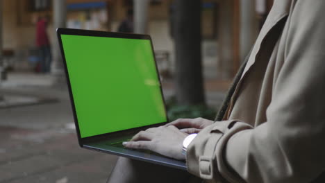 Student-Tippt-Laptop-Mit-Grünem-Bildschirm.-Frauenhände-Arbeiten-Am-Computer-Im-Freien
