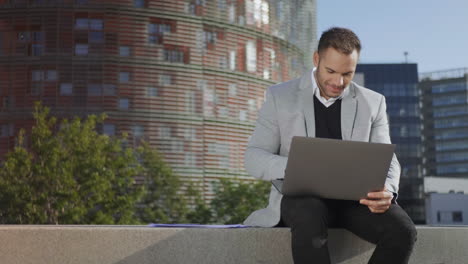 Businessman-reading-good-news-on-laptop-at-street.-Employee-working-on-laptop
