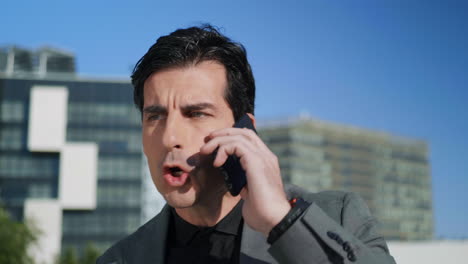 Businessman-talking-on-mobile-phone-at-street.Executive-arguing-on-phone-outside