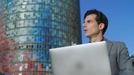 Businessman-browsing-internet-on-laptop-outdoors.-Professional-using-computer