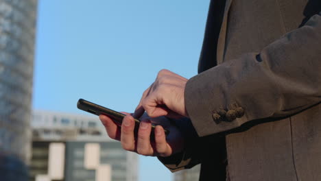 Businessman-hands-using-smartphone-on-street.-Employee-typing-message-on-phone