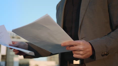 Businessman-hands-reading-documents-on-street.-Male-manager-keeping-papers