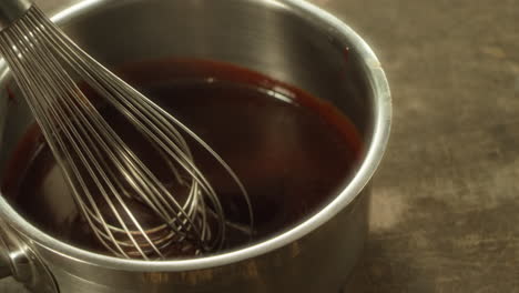 Closeup-metal-whisk-putting-into-melted-chocolate-in-slow-motion.