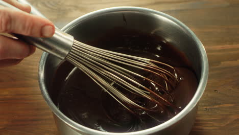 Closeup-chef-hand-mixing-liquid-chocolate-with-whisk-in-slow-motion.