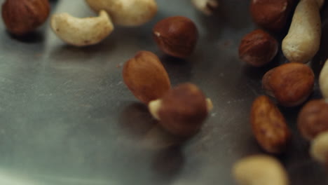 Macro-of-nuts-tossing-on-pan-in-slow-motion.-Closeup-cashews-and-hazel-nuts