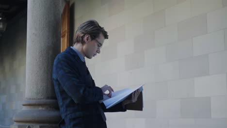 Student-reading-notes-in-notebook-at-university.-Businessman-looking-in-workbook