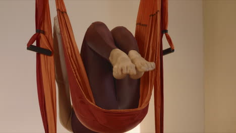 Woman-turning-body-in-air-at-studio.-Gymnast-performing-aero-yoga-indoors