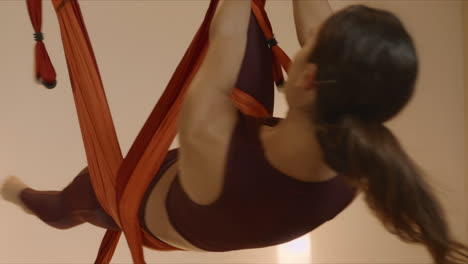 Gymnast-doing-backflip-in-hammock-at-studio.Woman-performing-aerial-yoga-indoors