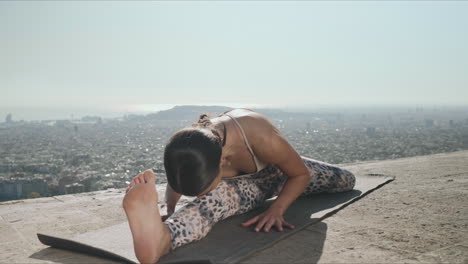Wwoman-performing-yoga-at-viewpoint-of-Barcelona.-Yoga-trainer-stretching-body